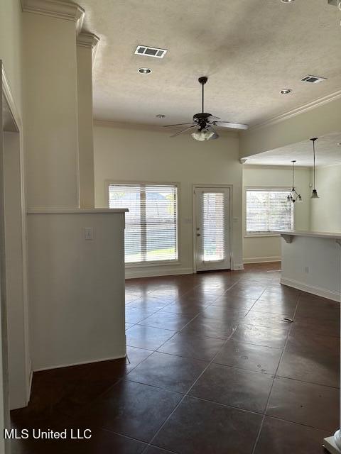 tiled empty room featuring ceiling fan and crown molding