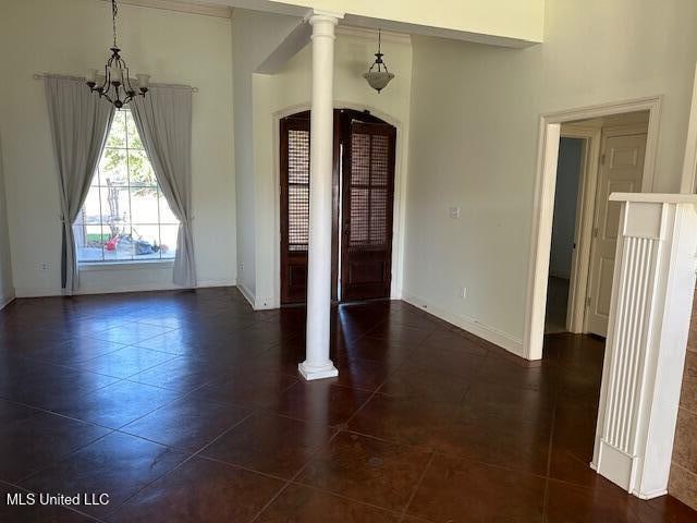 tiled entrance foyer featuring decorative columns and an inviting chandelier