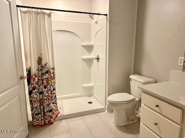 bathroom featuring tile patterned flooring, vanity, toilet, and curtained shower