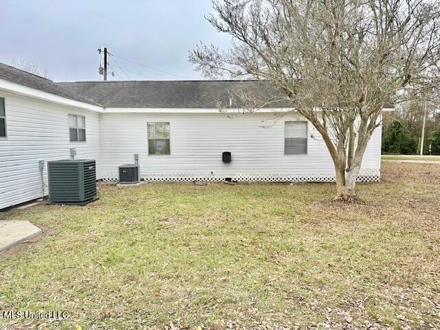 rear view of property with central AC and a yard