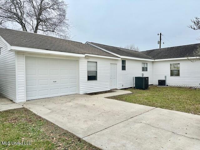 back of house with a yard, a garage, and cooling unit