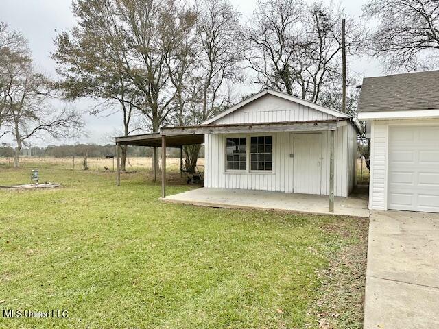 exterior space with a lawn, a garage, an outbuilding, and a carport