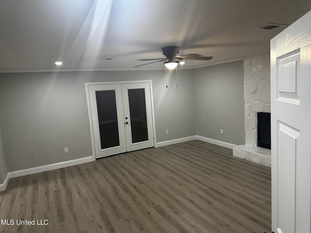 unfurnished living room with ceiling fan, a fireplace, ornamental molding, dark hardwood / wood-style flooring, and french doors