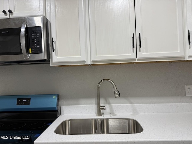 kitchen featuring light stone counters, stainless steel appliances, sink, and white cabinets