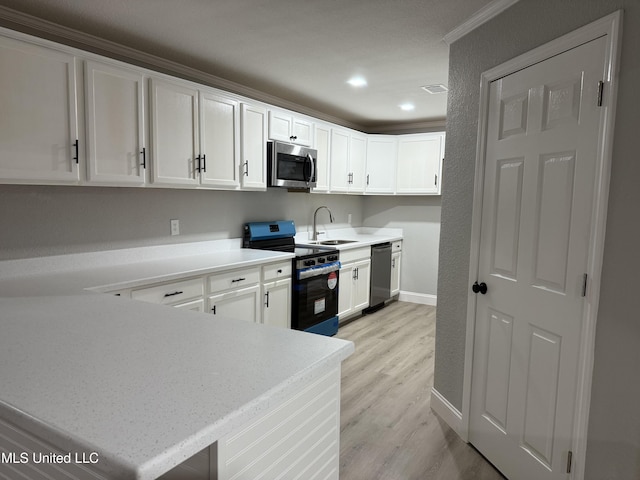 kitchen with sink, white cabinetry, light hardwood / wood-style flooring, appliances with stainless steel finishes, and kitchen peninsula