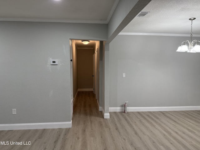 empty room featuring crown molding, a chandelier, a textured ceiling, and light hardwood / wood-style floors