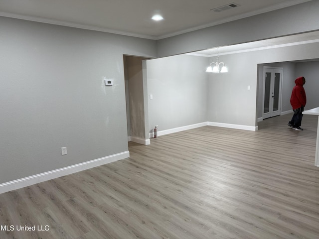 basement featuring light hardwood / wood-style flooring, ornamental molding, and a chandelier