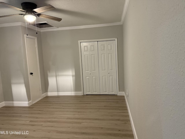 unfurnished bedroom with hardwood / wood-style floors, crown molding, a closet, and ceiling fan