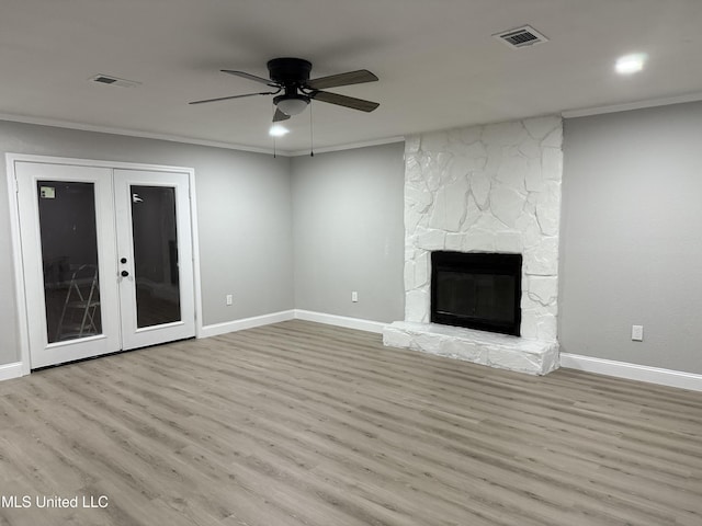 unfurnished living room featuring crown molding, a stone fireplace, and light hardwood / wood-style floors