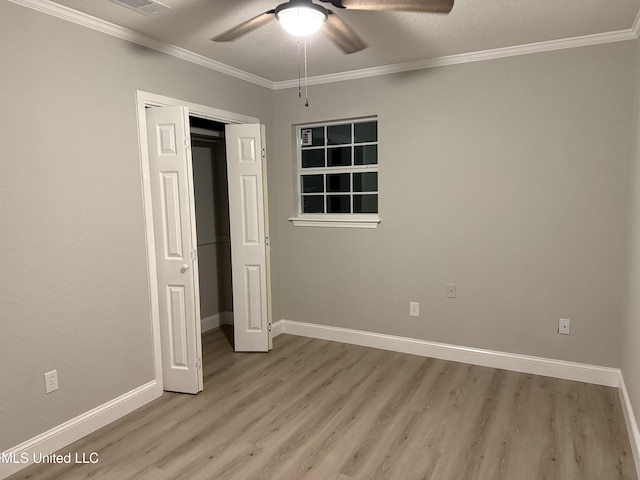 unfurnished bedroom with crown molding, light hardwood / wood-style flooring, a closet, and ceiling fan