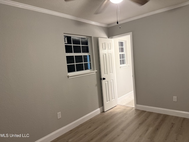 empty room with crown molding, wood-type flooring, and ceiling fan