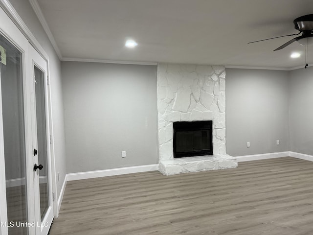 unfurnished living room featuring ceiling fan, ornamental molding, a fireplace, and light wood-type flooring