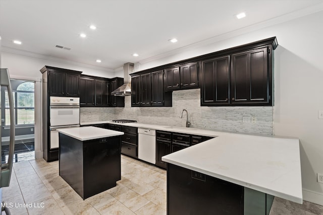 kitchen featuring wall chimney range hood, ornamental molding, sink, a center island, and white appliances