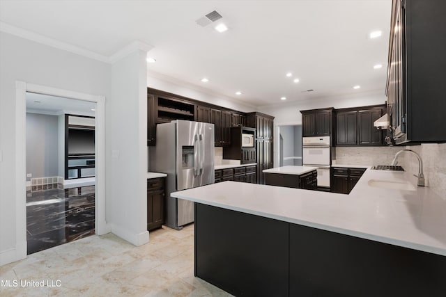 kitchen featuring kitchen peninsula, backsplash, ornamental molding, a center island, and white appliances