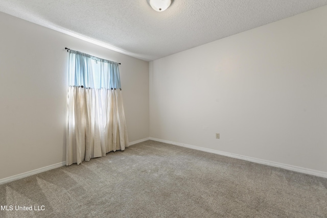 carpeted spare room featuring a textured ceiling and baseboards