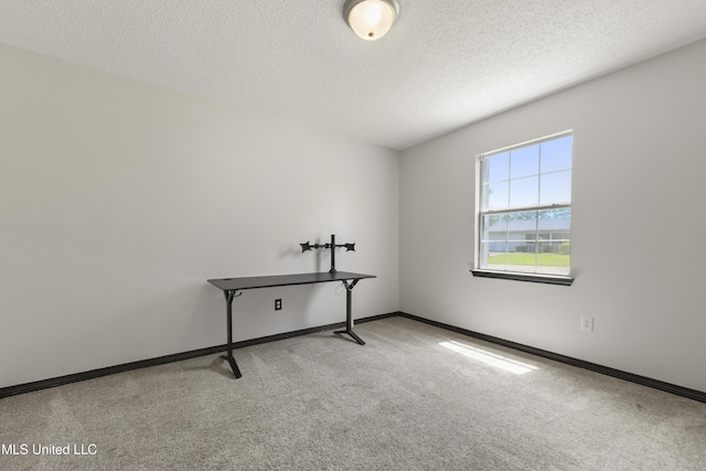 carpeted empty room featuring a textured ceiling and baseboards