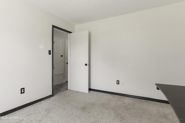 unfurnished room with baseboards, visible vents, a textured ceiling, and light colored carpet