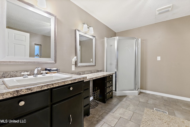 bathroom with a textured ceiling, vanity, vaulted ceiling, and walk in shower