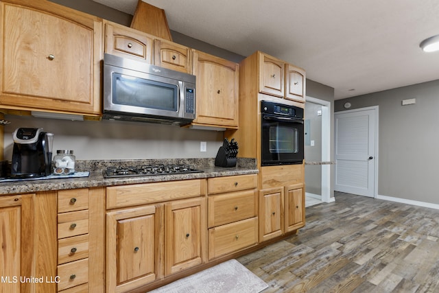 kitchen featuring light brown cabinetry, appliances with stainless steel finishes, and wood-type flooring