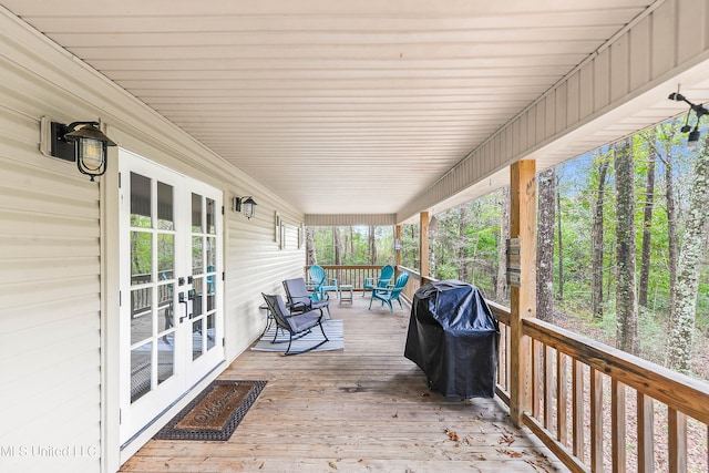 wooden deck featuring covered porch, french doors, and a grill