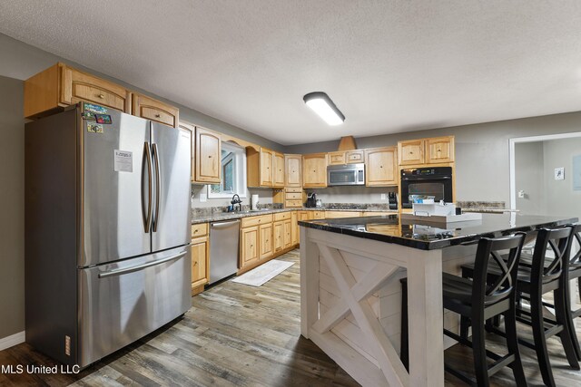 1160 Lucas Rd, Lucedale, MS 39452 - kitchen featuring stainless steel appliances, light brown cabinets, wood finished floors, a breakfast bar, and a kitchen island