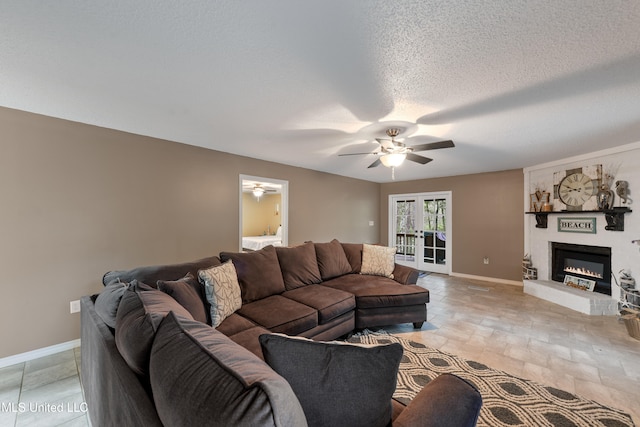 living room with a fireplace, ceiling fan, and a textured ceiling