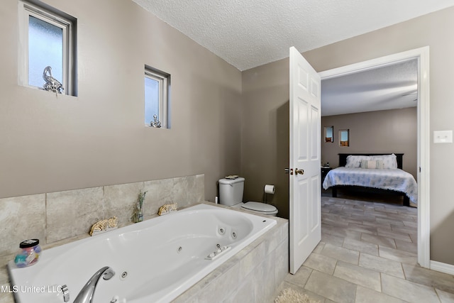 bathroom with tile patterned floors, tiled bath, a textured ceiling, and toilet