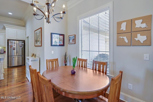 dining space with an inviting chandelier, baseboards, ornamental molding, and wood finished floors