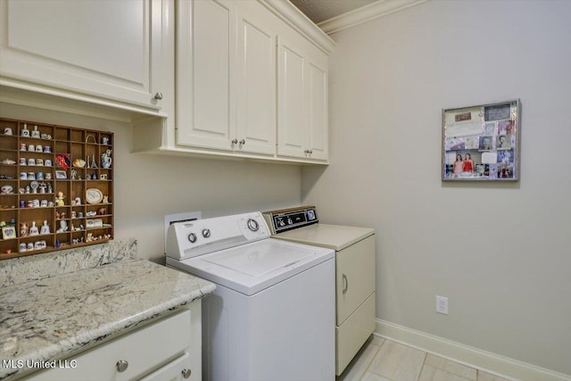 clothes washing area with washer and dryer, cabinet space, and baseboards