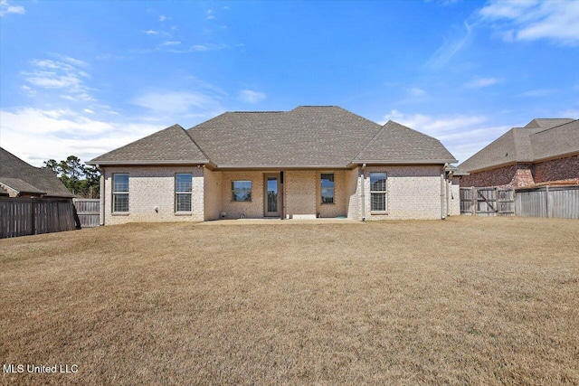 back of house with a shingled roof, a fenced backyard, and a lawn