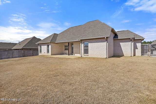 back of property with a fenced backyard, a yard, brick siding, and a patio