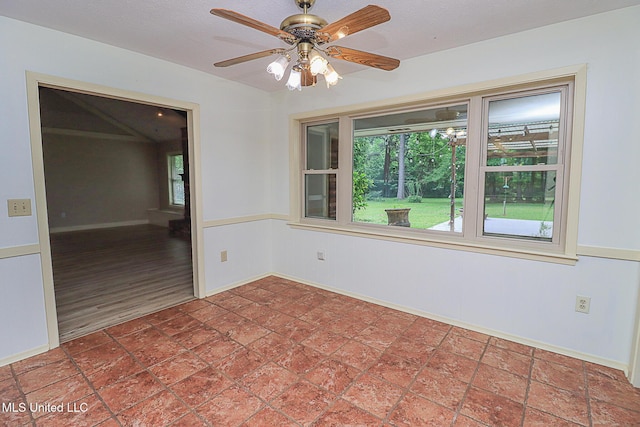 spare room featuring a ceiling fan and baseboards