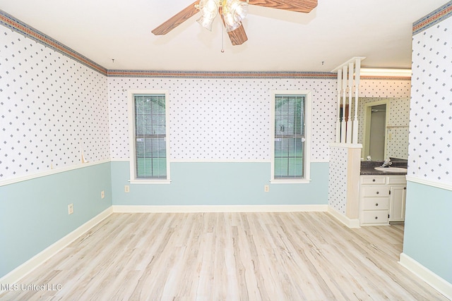 spare room featuring ceiling fan, wood finished floors, baseboards, and a sink