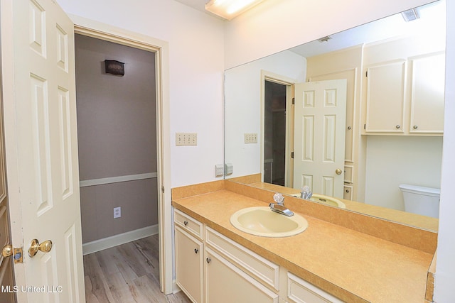 bathroom featuring wood finished floors, toilet, and vanity