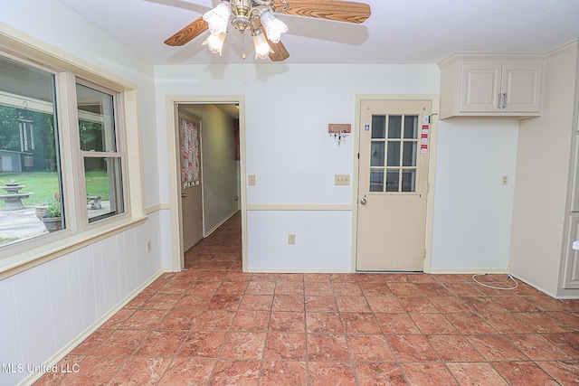 empty room featuring a ceiling fan and baseboards