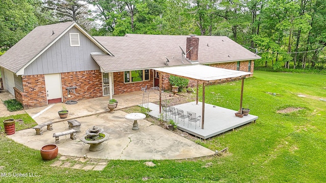 back of property featuring a yard, a deck, brick siding, a patio area, and roof with shingles