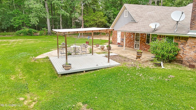view of green lawn featuring a patio area and a deck