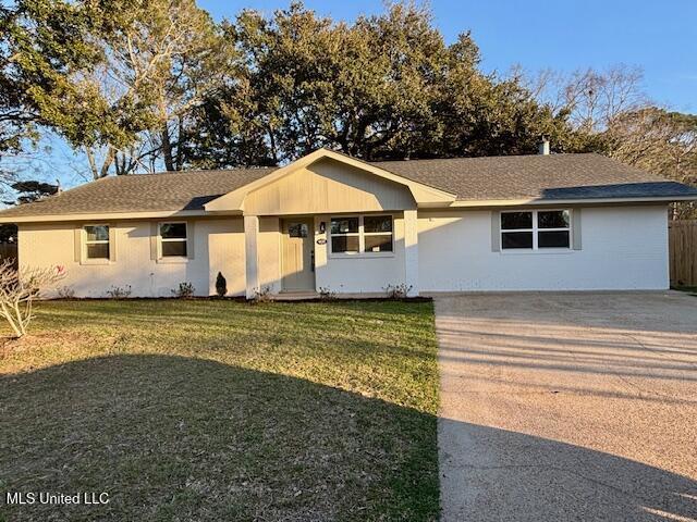 single story home with concrete driveway, a front yard, and fence