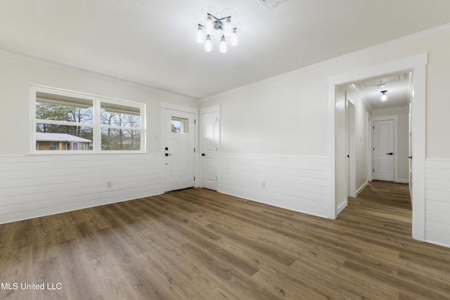 spare room featuring wainscoting, wood finished floors, and crown molding