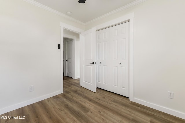 unfurnished bedroom featuring ornamental molding, a closet, baseboards, and wood finished floors