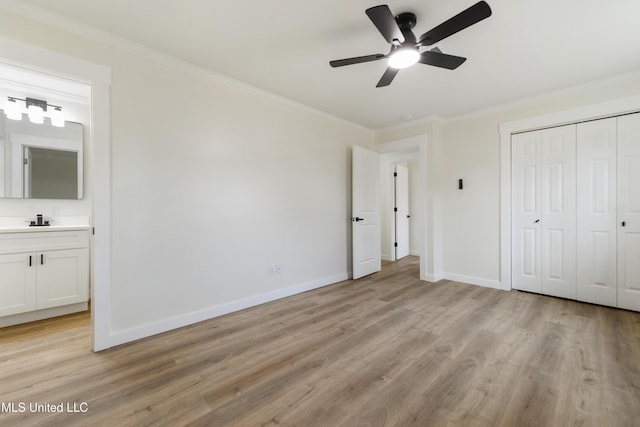 unfurnished bedroom with ornamental molding, a closet, light wood-style flooring, and baseboards