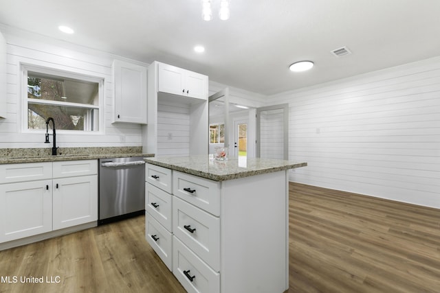 kitchen with white cabinets, visible vents, stainless steel dishwasher, and wood finished floors