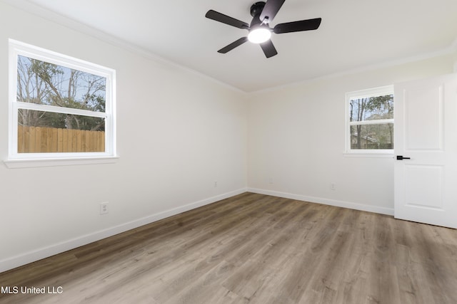 spare room with baseboards, ceiling fan, wood finished floors, and crown molding