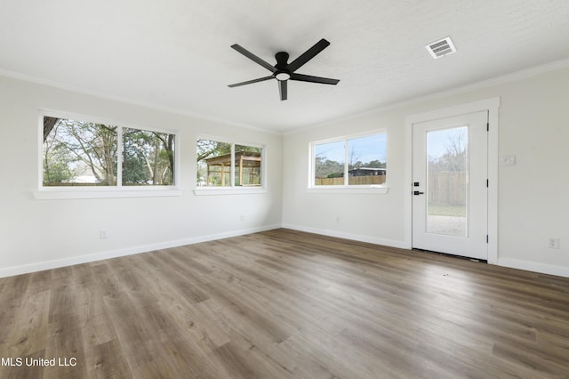 interior space featuring visible vents, ornamental molding, a ceiling fan, wood finished floors, and baseboards