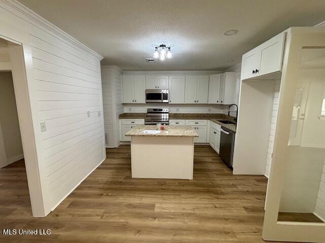 kitchen with white cabinetry, stainless steel appliances, a sink, and wood finished floors