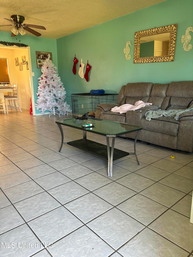 living room with ceiling fan, light tile patterned floors, and a textured ceiling