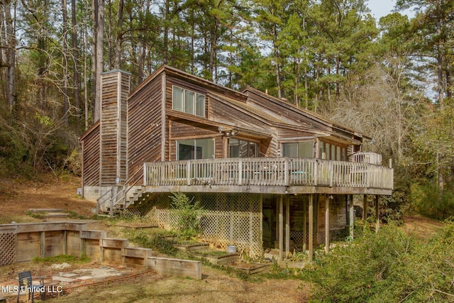 back of house with a deck, stairway, and a chimney