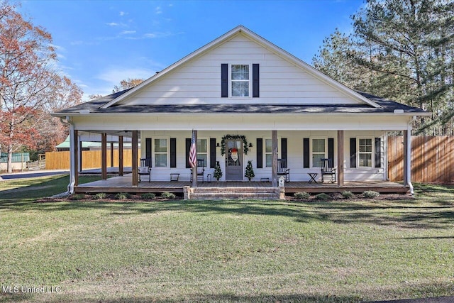 farmhouse-style home with covered porch, fence, and a front yard