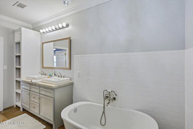 full bathroom with double vanity, a freestanding tub, a sink, and crown molding