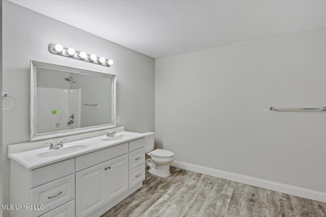 bathroom featuring toilet, a shower, a sink, and wood finished floors